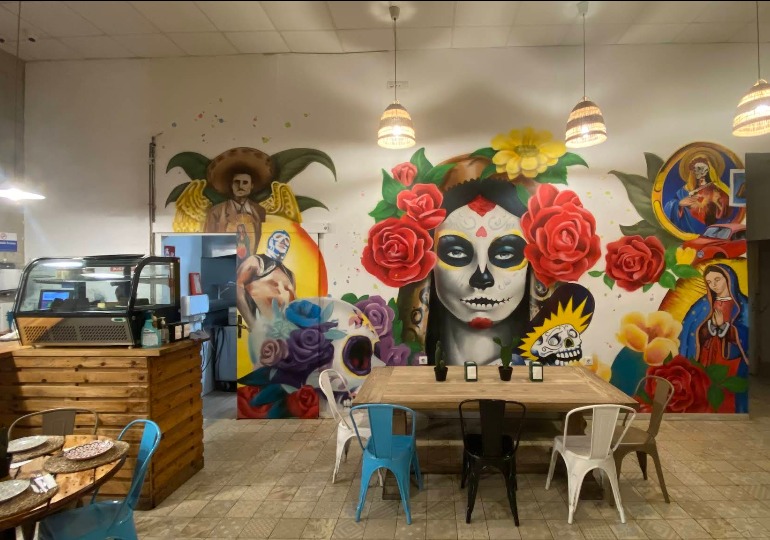 Zona de mesas con mural artistico en La Bigotuda